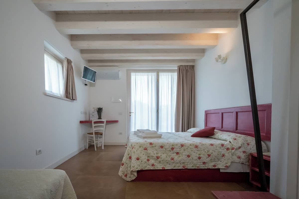 Ein Schlafzimmer mit einem Bett, einem Schreibtisch, einem Stuhl, einem Fernseher und einem Fenster.