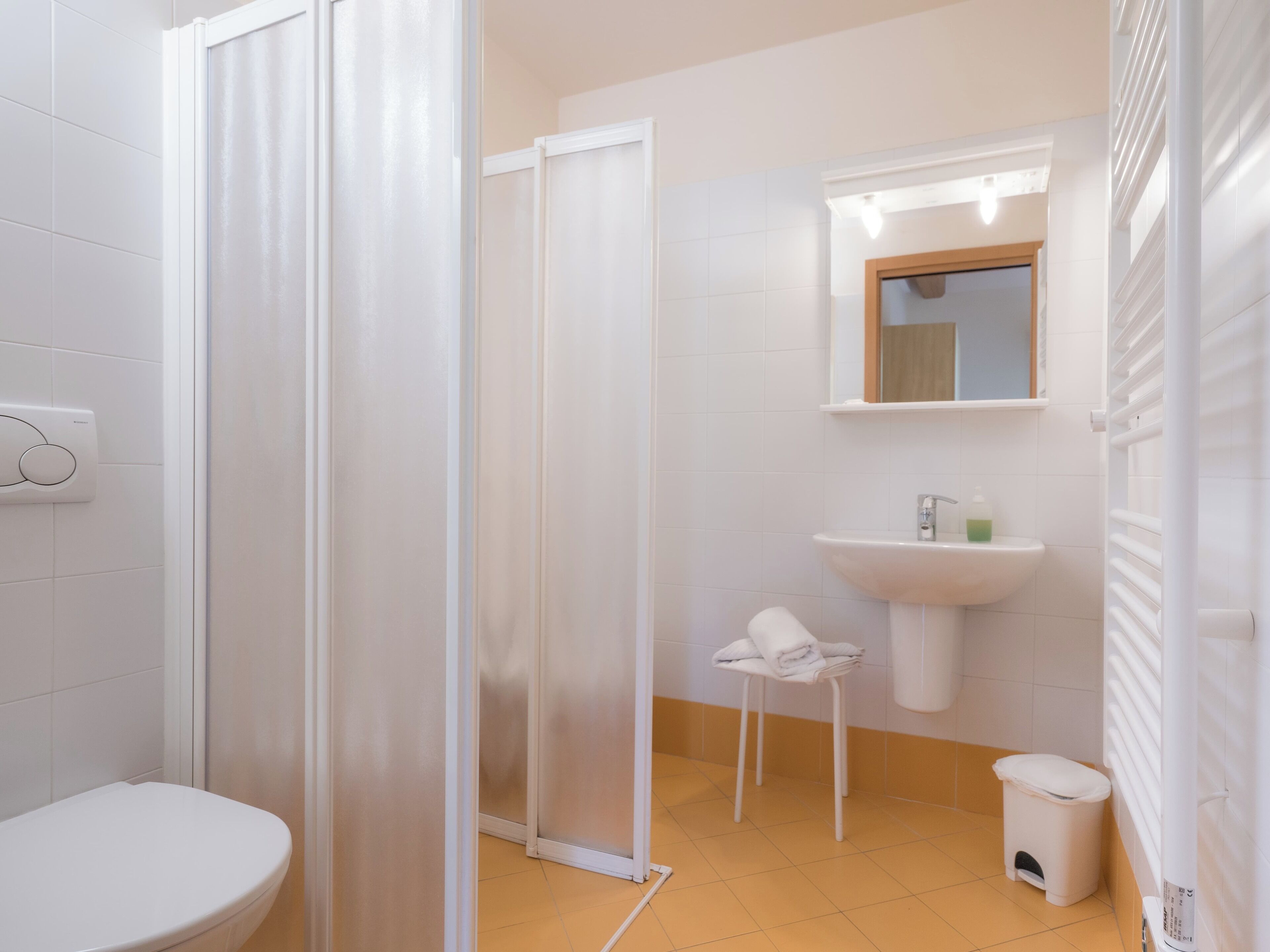 A modern bathroom with a toilet, a sink, a mirror, and a shower enclosure.
