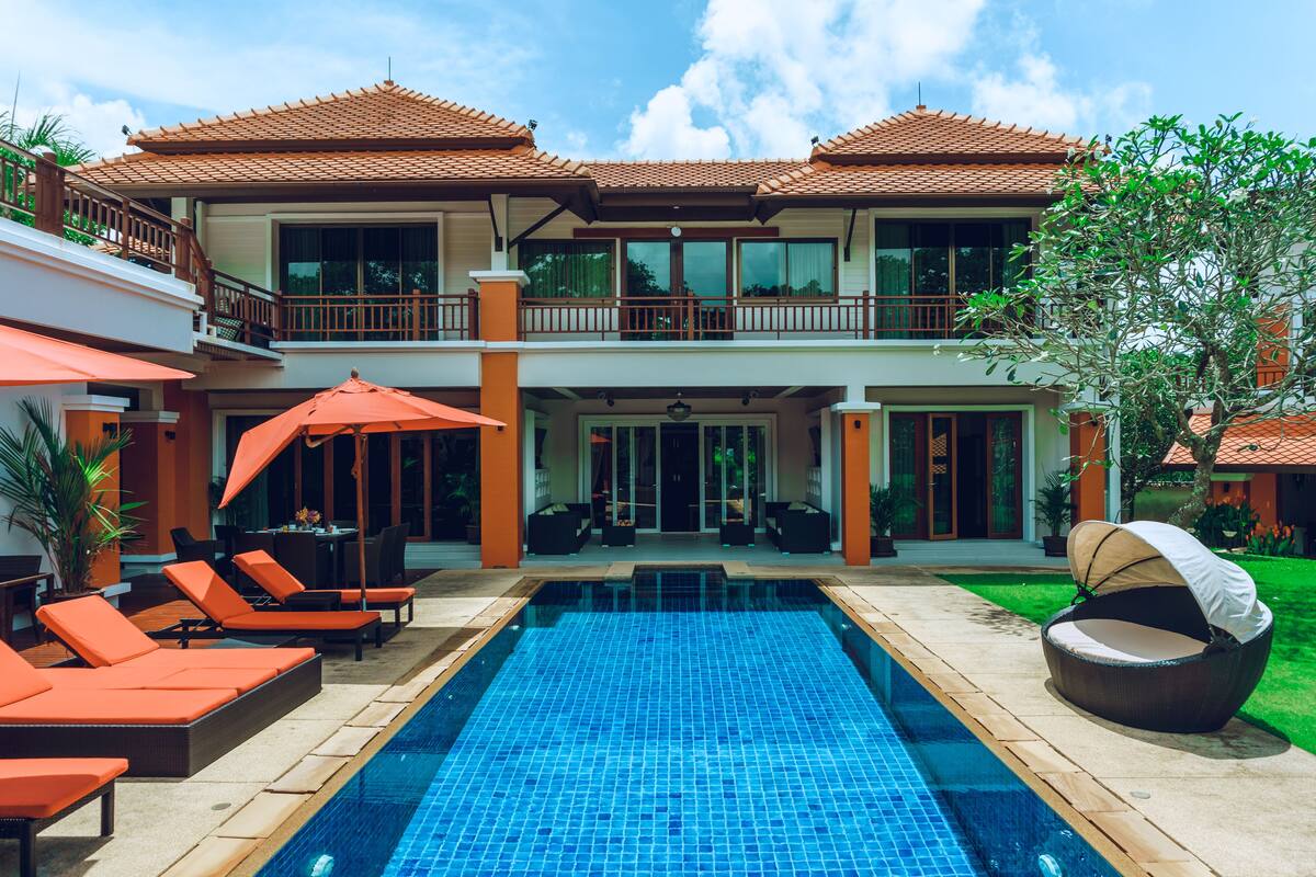 A two-story house with a swimming pool, outdoor seating, and a covered patio area.