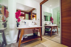 Ein modernes Badezimmer mit zwei Waschbecken, einem Holz-Waschtisch und großen Spiegeln.