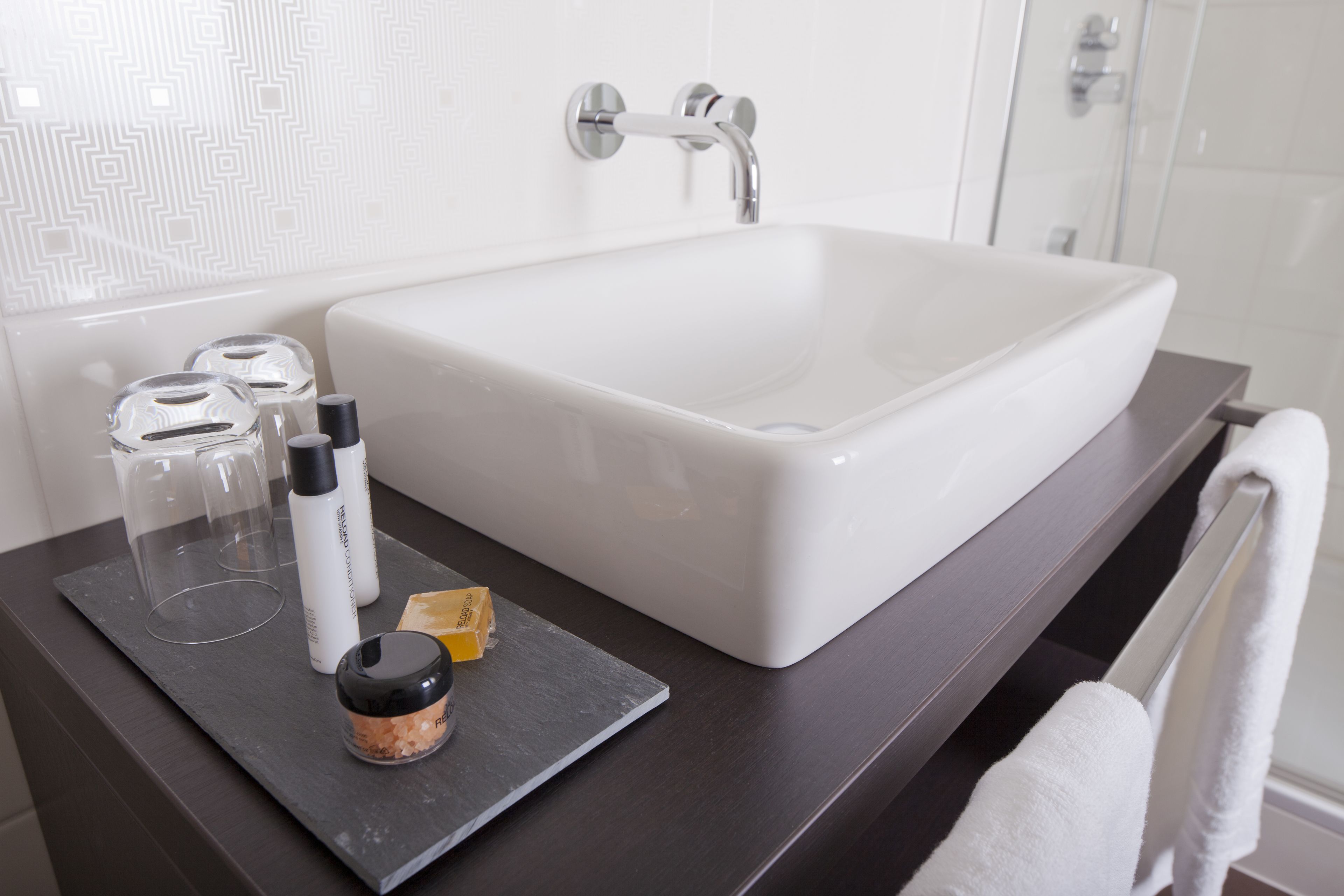 A bathroom with a white sink, a dark countertop, and a glass shower enclosure.
