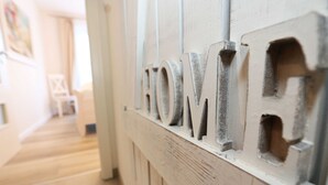 Un pasillo con suelo de madera y pared blanca donde se lee la palabra 'HOME' en letras grandes.
