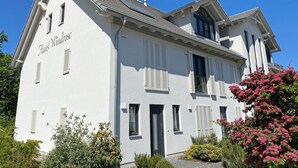 Un edificio de dos pisos con fachada blanca, contraventanas y cielo despejado.