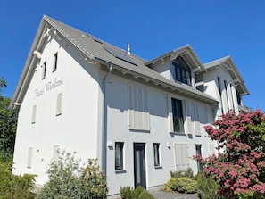 A two-story building with a white facade, shutters, and a clear sky.