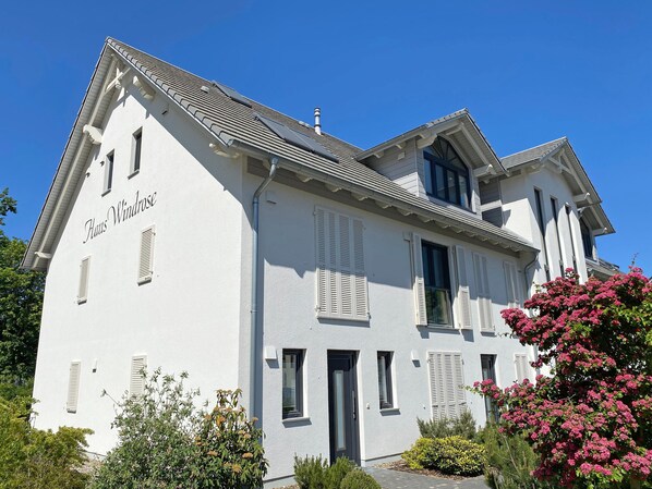 Un bâtiment à deux étages, doté d’une façade blanche, de volets et surplombant un ciel dégagé.