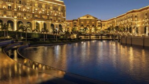 A large, well-lit hotel with multiple buildings connected by a water feature. - The St. Regis New Capital, Cairo (New Capital)