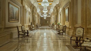 A long, elegant hallway with chandeliers, ornate chairs, and framed artwork on the walls. - The St. Regis New Capital, Cairo (New Capital)