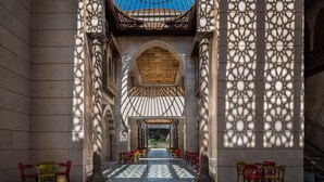 An interior with a central arched corridor, patterned floor, and a ceiling with a blue dome. - The St. Regis New Capital, Cairo (New Capital)