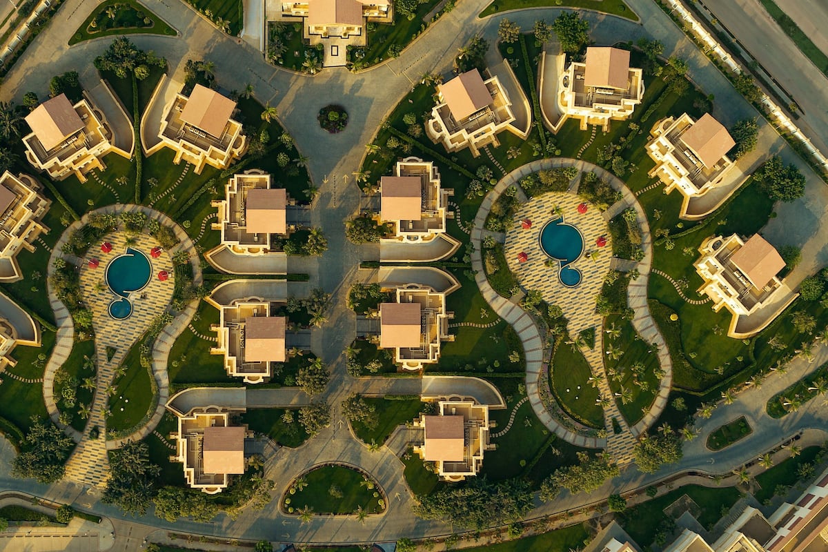 An aerial view of a residential area with multiple houses, roads, and circular driveways.