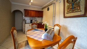 A dining area with a wooden table, chairs, a toaster, and a small potted plant.