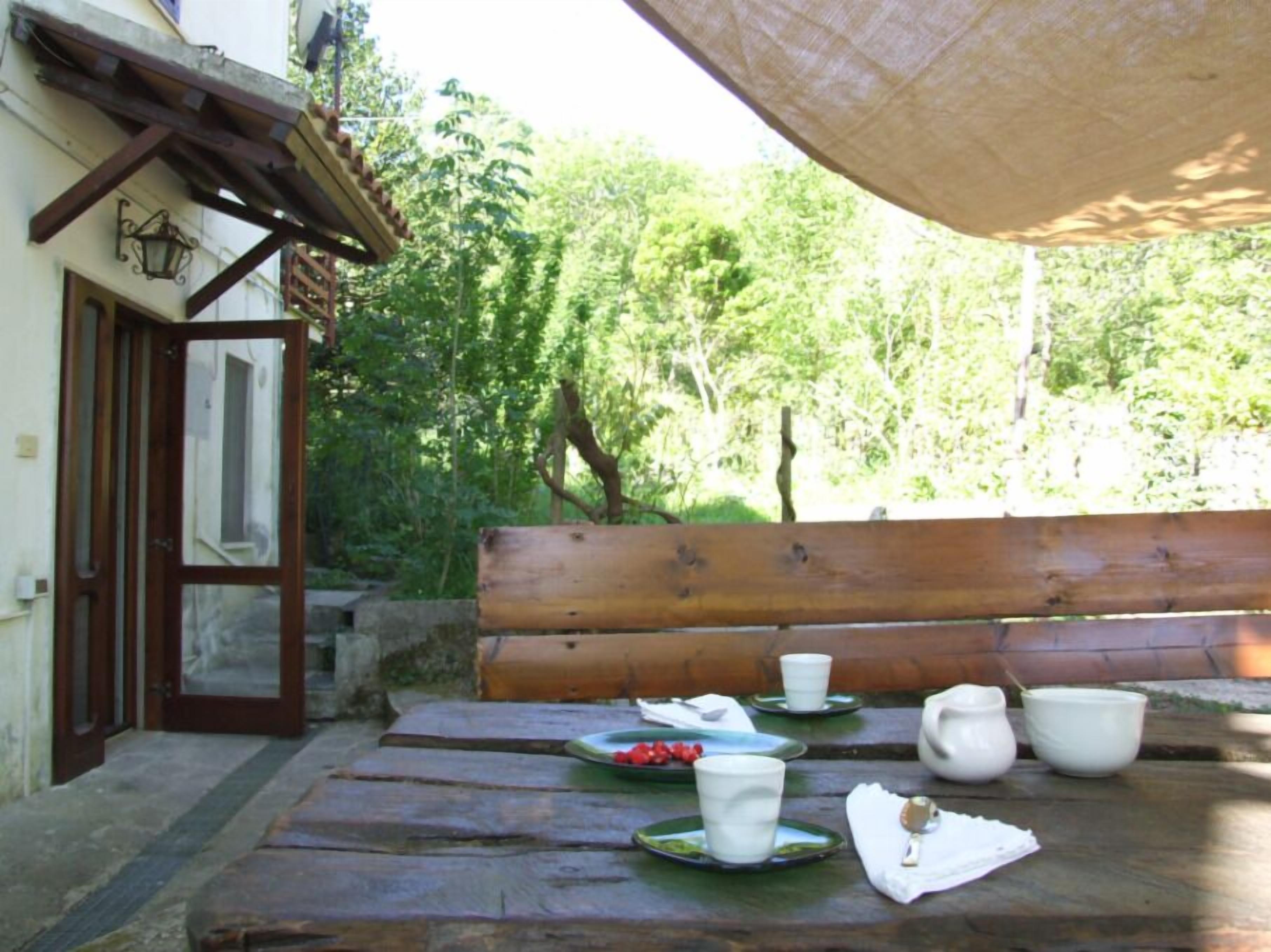 An outdoor dining area with a wooden bench and a table set for tea service.