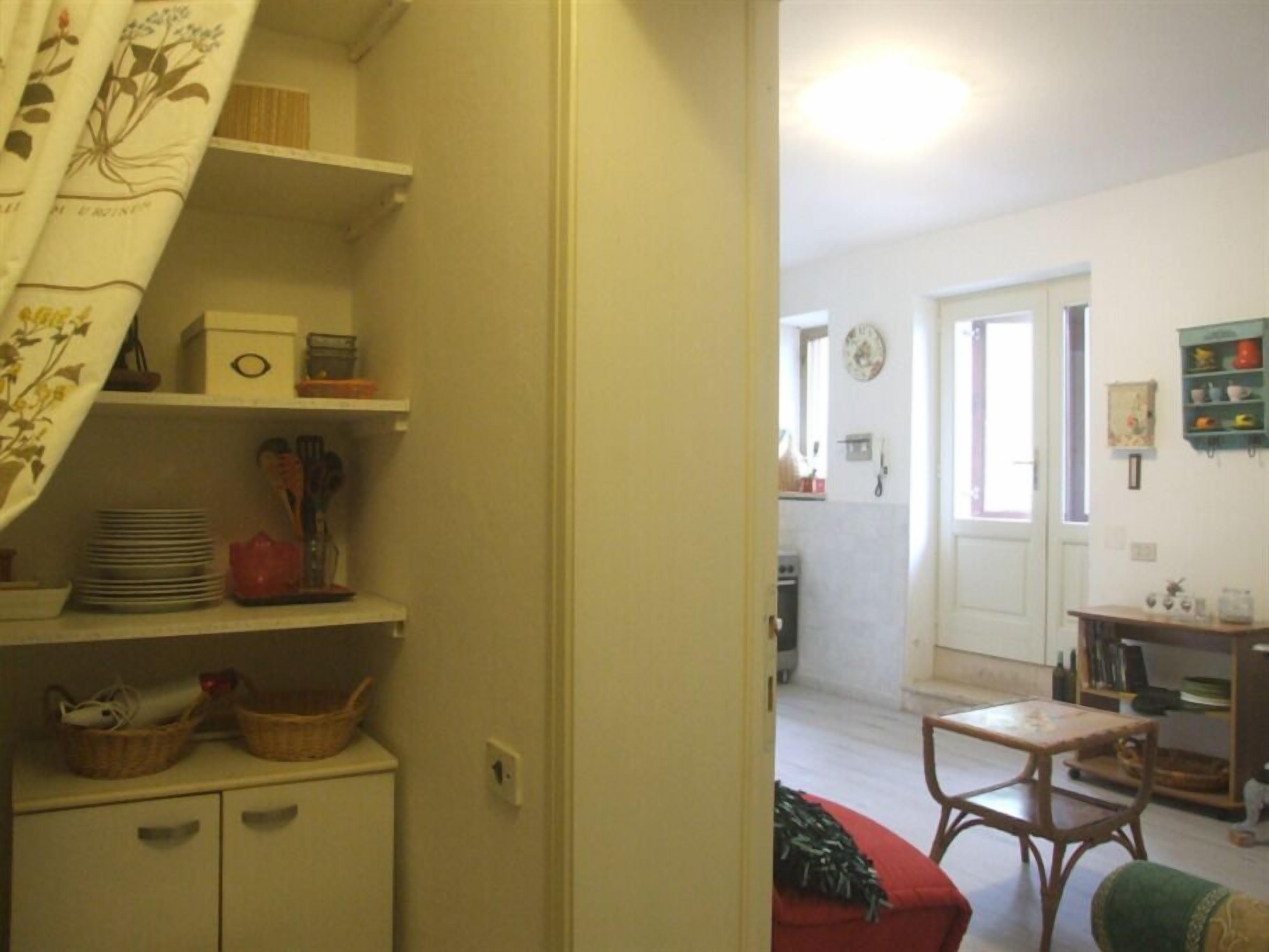 Una habitació amb zona de cuina, taula de dinar i sofà vermell.