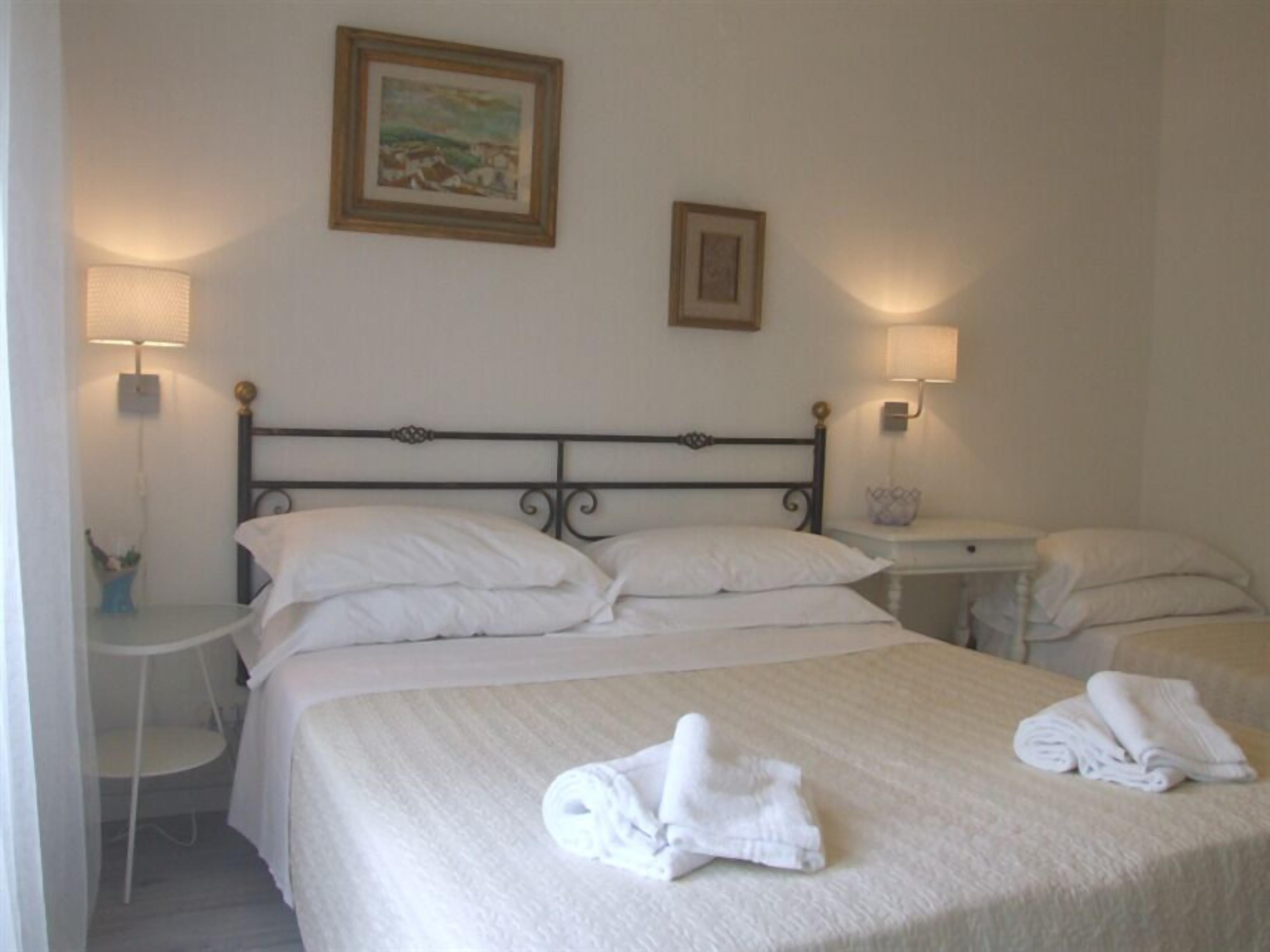 A hotel room with a bed, two bedside tables, and two wall-mounted lamps.