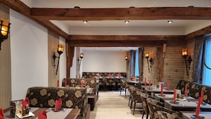 Un restaurante con vigas de madera, tapicería floral y mesas iluminadas con velas.