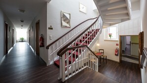 Un pasillo espacioso con una escalera de madera que conduce a una zona de descanso.