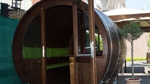 Una estructura de madera con una entrada curva, un interior verde y un árbol en maceta afuera.