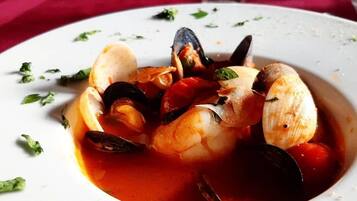 Un plato de mariscos sobre una fuente blanca con un mantel rojo de fondo.