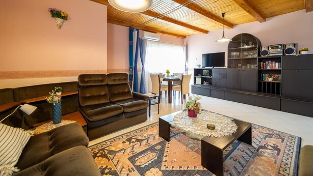 A living room with a sofa, a coffee table, and a TV. There is a bookshelf and a dining area in the background. - Cedar  Apartment 3 - One Bedroom Apartment, Sleeps 4 (Zalakaros)