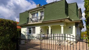A two-story building with a green roof, a balcony on the upper floor, and a gated entrance. - Cedar  Apartment 3 - One Bedroom Apartment, Sleeps 4 (Zalakaros)