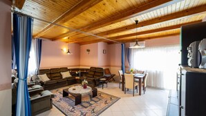 A cozy living room with a sectional sofa, a coffee table, and a dining area with chairs and a table. - Cedar  Apartment 3 - One Bedroom Apartment, Sleeps 4 (Zalakaros)