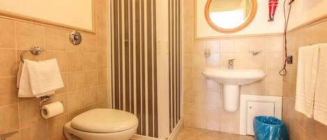 A bathroom with a toilet, bidet, sink, shower, and a mirror.