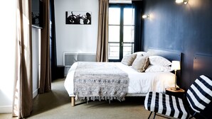 A modern bedroom with a bed, a chair, a bedside table, and a window. - Hôtel Le Collonges (Brive-la-Gaillarde)