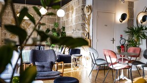 A cozy living room with a stone wall, modern furniture, and decorative plants. - Hôtel Le Collonges (Brive-la-Gaillarde)