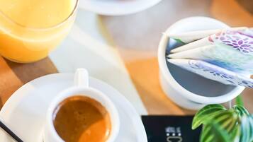 Une table mise pour le petit-déjeuner avec une assiette de fruits, un verre de jus d’orange, une tasse de café et un menu.