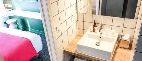 A modern bathroom with a white sink, mirror, and towel rack.