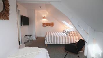 A bedroom with a bed, a chair, a TV, and a unique sloped ceiling.