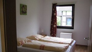 Un dormitorio con dos camas, una ventana con cortinas, un radiador y una puerta.