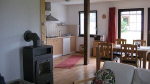 Cocina con estufa, microondas y armarios. Hay un comedor con sillas y una mesa.