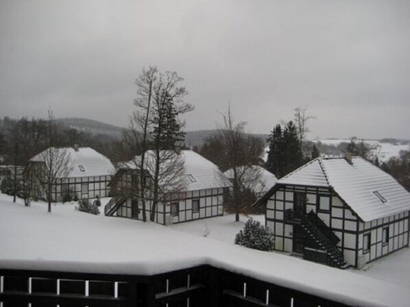 A row of modern, snow-covered buildings with large windows and flat roofs, surrounded by trees and a hilly landscape in the background. - Am Sternberg 209 - Two Bedroom Resort, Sleeps 6 (Frankenau)