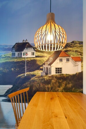 Un tavolo da pranzo con una sedia di legno, un lampadario e un affresco raffigurante case su una collina.