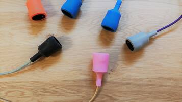 A wooden surface with five different colored and shaped objects, possibly parts of electronic devices or tools.