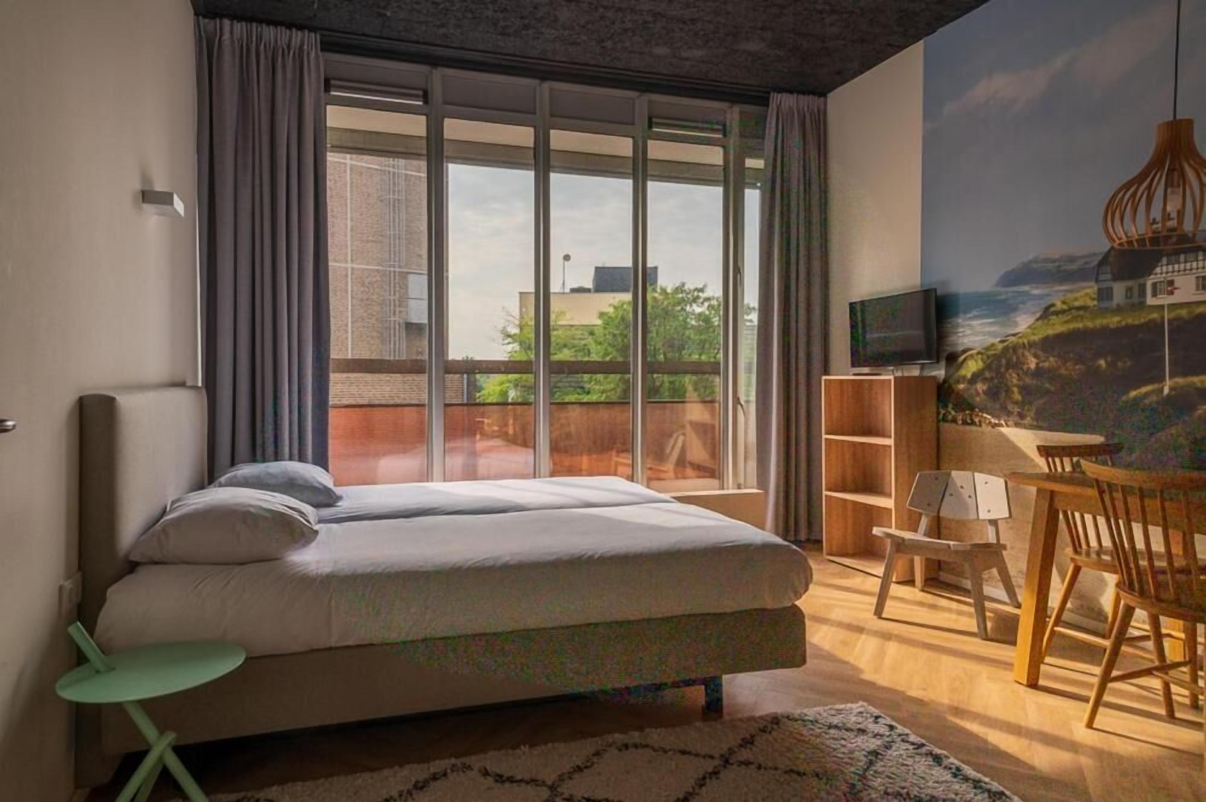 Une chambre avec un grand lit, une télévision, une chaise en bois et une bibliothèque.