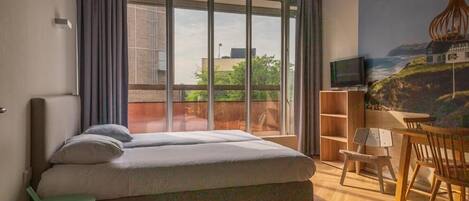A bedroom with a large bed, a TV, a wooden chair, and a bookshelf.