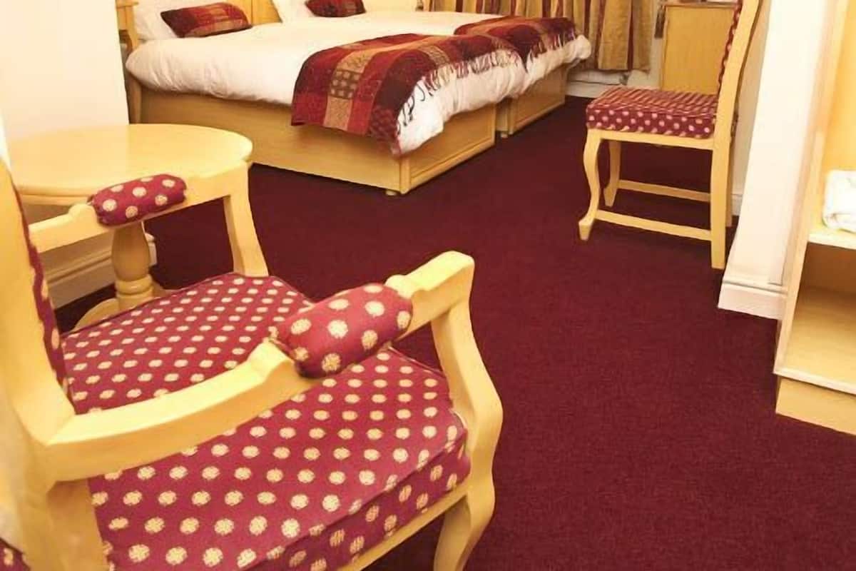 A hotel room with two beds, a small table, two chairs, and a television.