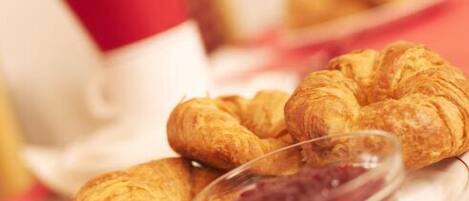 A plate with croissants and a small bowl of jam.
