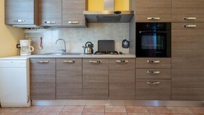 A modern kitchen with wooden cabinets, a built-in oven, a coffee maker, and a kettle. - Casa Lucia 1 - Three Bedroom Apartment, Sleeps 5 (Idro)