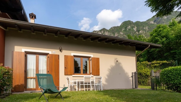 A two-story house with a balcony, a dining area with a table and chairs, and a green folding chair in the yard. - Casa Lucia 1 - Three Bedroom Apartment, Sleeps 5 (Idro)