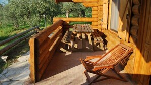 Una terraza de madera con una mesa de picnic y una silla de salón.