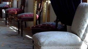 A room with a large window, wooden walls, a chandelier, and ornate furniture including a chair and ottoman. - A Hotel Boutique Pelluhue (Pelluhue)
