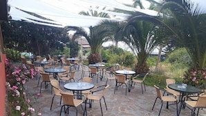 An outdoor patio area with stone flooring and round tables with chairs. - A Hotel Boutique Pelluhue (Pelluhue)