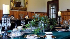 A formal dining table set with crystal glassware, silverware, and a vase of green foliage. - A Hotel Boutique Pelluhue (Pelluhue)