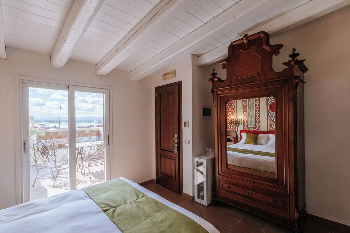 Une chambre à coucher comprenant un lit, une armoire, un miroir et une porte coulissante donnant sur un balcon.