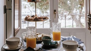 Een ontbijttafel met een etagère vol desserts, een glas sinaasappelsap en een kop koffie.