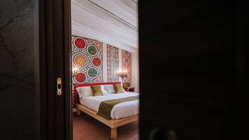 Une chambre avec un lit en bois, une tête de lit à motifs et un sol carrelé.