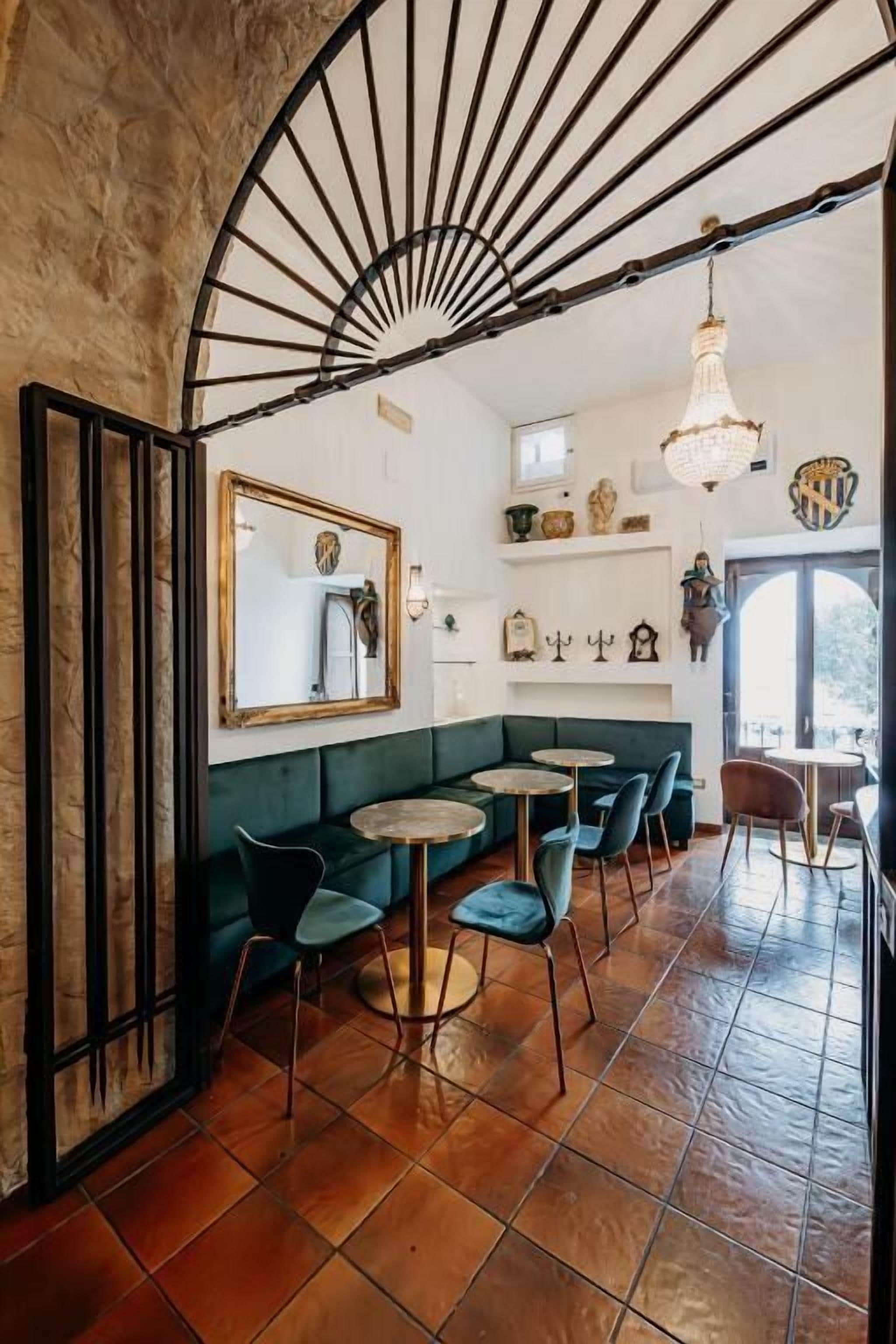 Un interior acogedor con un sofá verde, mesas redondas y un ventilador.