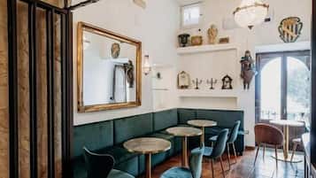 Un interior acogedor con un sofá verde, mesas redondas y un ventilador.